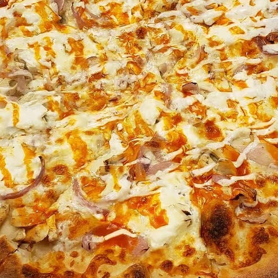 Large rectangular pizza topped with melted cheese, chicken, mushrooms, onions, peppers, and browned crust.